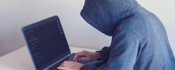 Programmeur en sweat à capuche tapant sur un ordinateur portable avec un écran de code