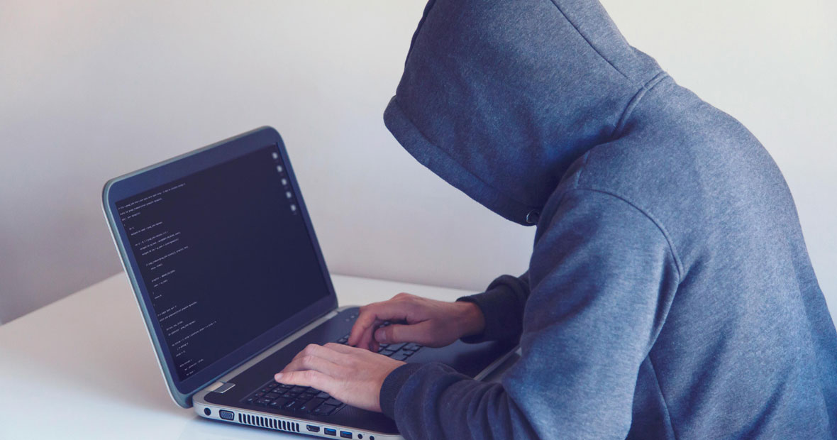 Programmeur en sweat à capuche tapant sur un ordinateur portable avec un écran de code